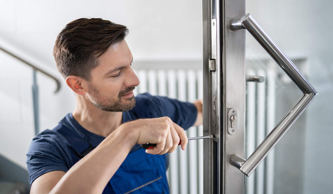 電気錠をつけるために開き戸の扉を工事しようとしている男性